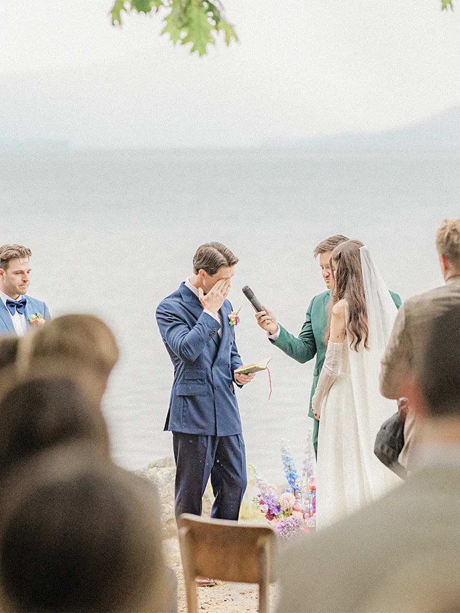 The groom reading his vows into a handheld mic at a lakeside VARA wedding