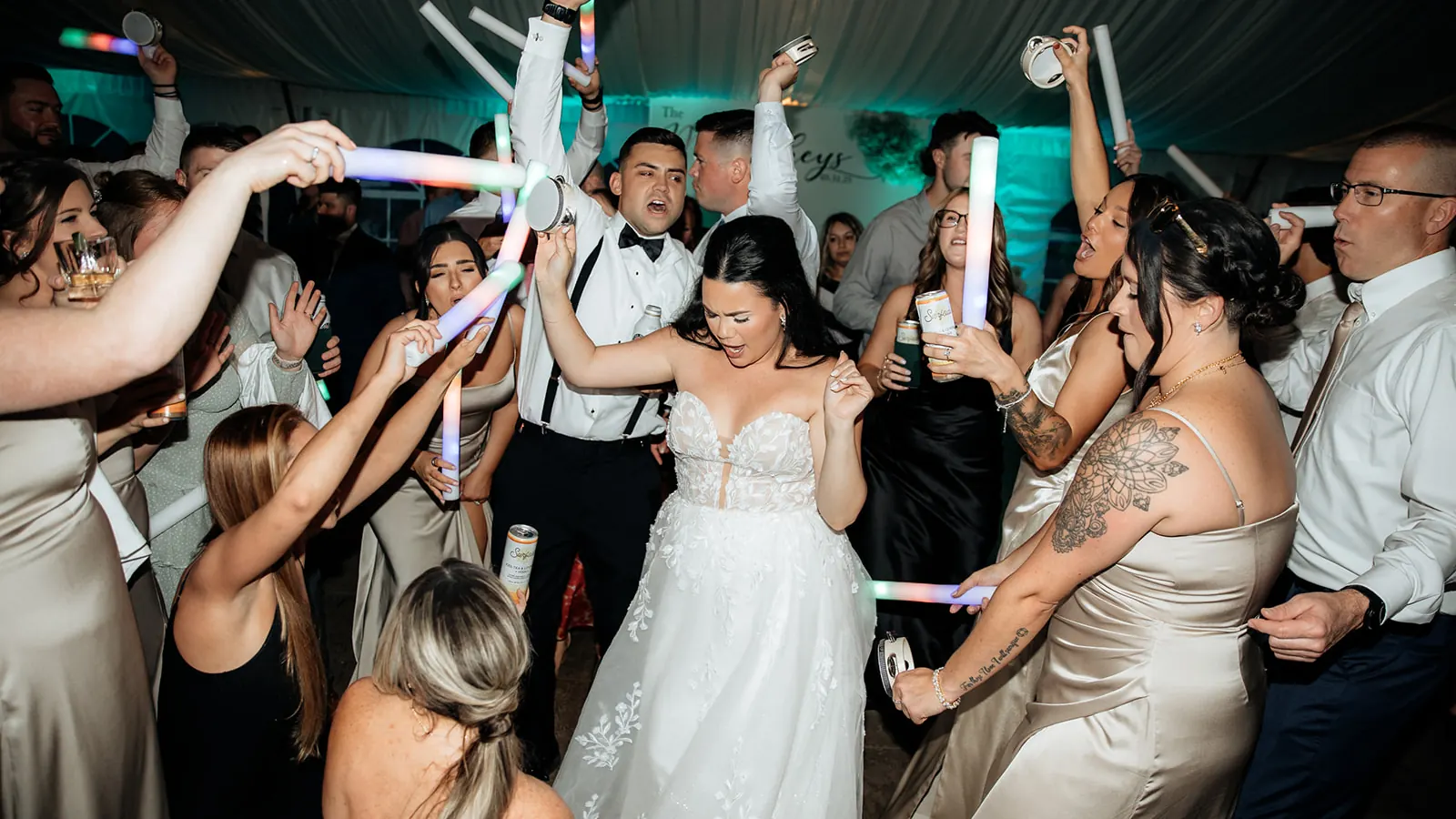 The bride dancing in a packed crowd waving LED foam sticks at a VARA wedding