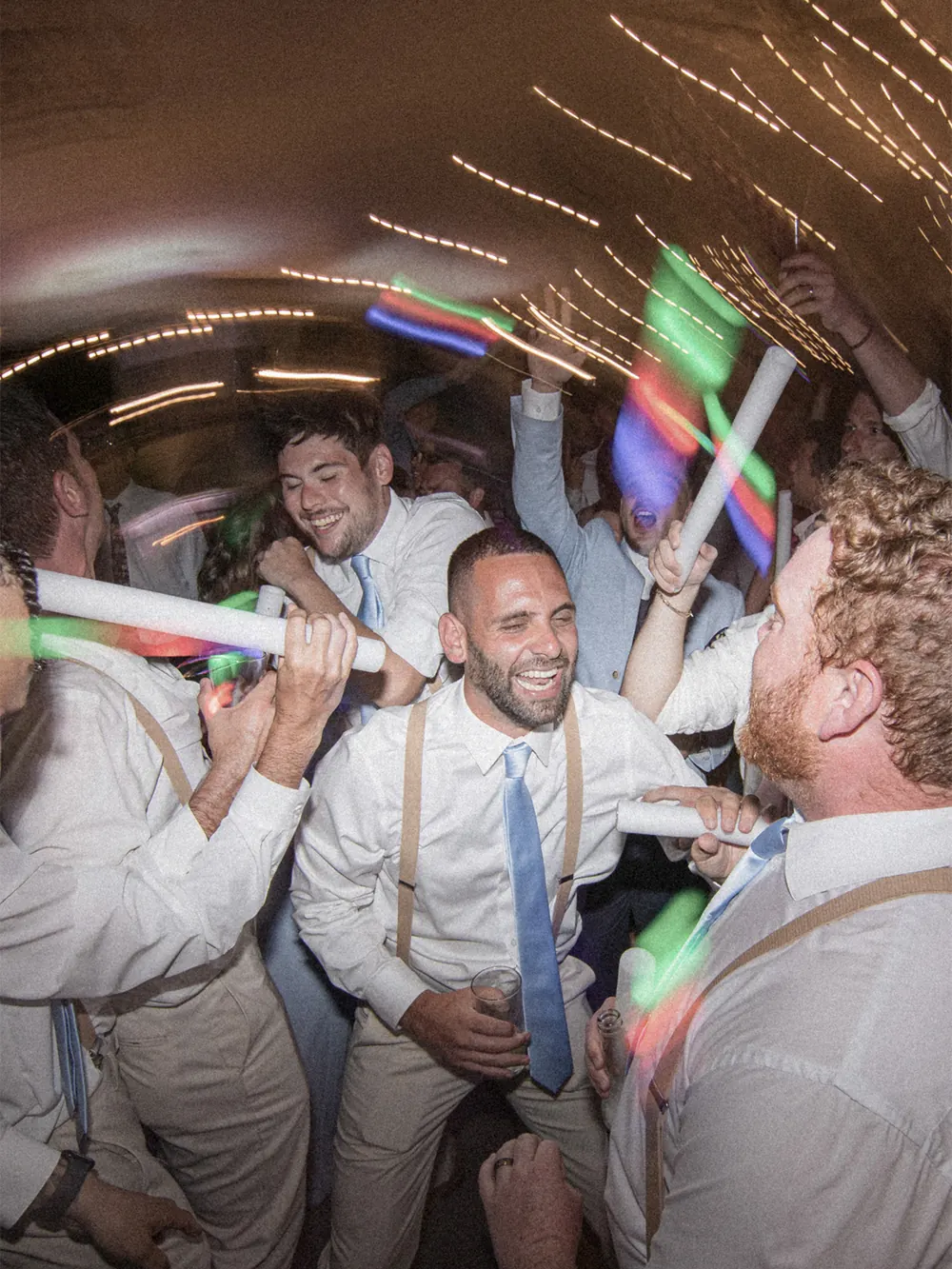 Groomsmen dancing with LED foam sticks at a VARA wedding reception